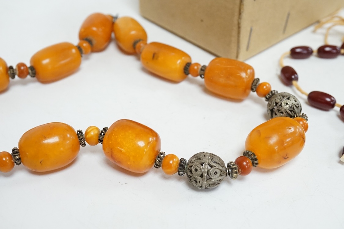 A single strand amber bead necklace, with filigree metal spacers, 48cm, gross 84 grams, together with a group of loose graduated simulated cherry amber beads, gross weight 117 grams.